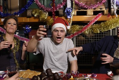 Group of workers toasting with wine glasses at Christmas table in warehouse, portrait