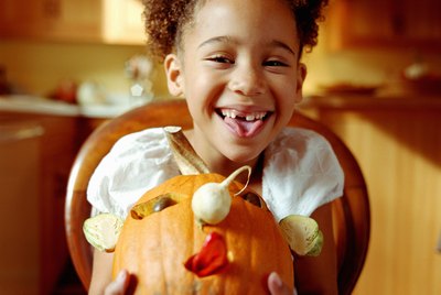 Girl (6-8) holding decorated pumpkin, smiling, portrait
