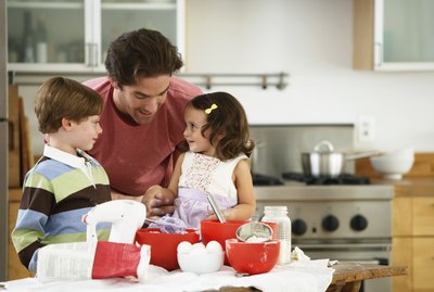 Father, son (5-7) and daughter (2-4) baking in kitchen