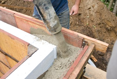 Construction worker pouring concrete in wall mold