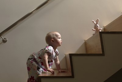 Baby girl climbing stairs to get toy