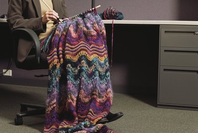 Businesswoman sitting at a desk knitting
