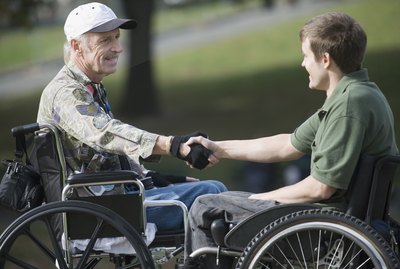 Side profile of a mature war veteran shaking hands with a young man