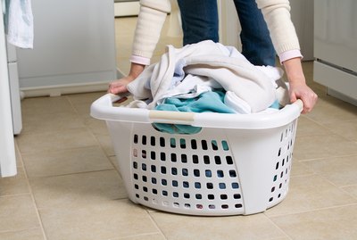 Cropped shot of woman picking up basket of laundry