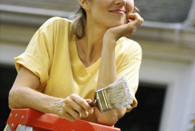 Woman posing by ladder with paintbrush