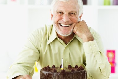 portrait of a senior man smiling in front of a birthday cake