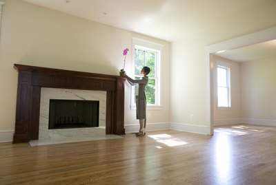 Woman placing orchid on fireplace in empty room