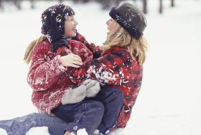 Mother and daughter (6-7) sitting in snow
