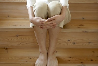 Woman with bare feet, sitting on wooden stairs in home