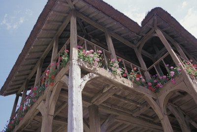 Low angle view of cottage with balcony and flowers