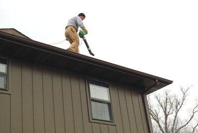 Homeowner Cleaning Eaves Using a Leaf Blower