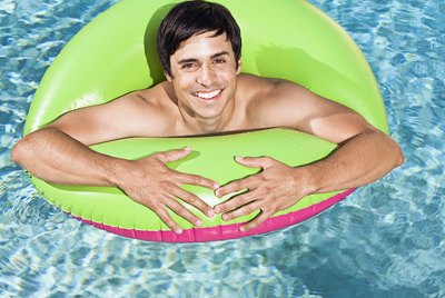 Man in swimming pool with flotation device