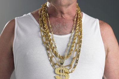 Senior man wearing tank top and gold chains with dollar sign, mid section