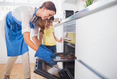 Smiling mother taking cookies out of the oven