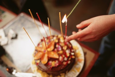 Person lighting candles on birthday cake