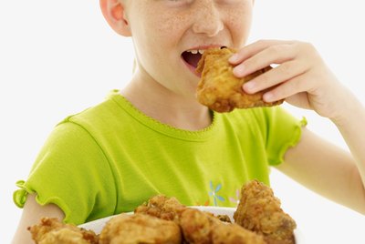 portrait of a girl (6-9) eating fried chicken