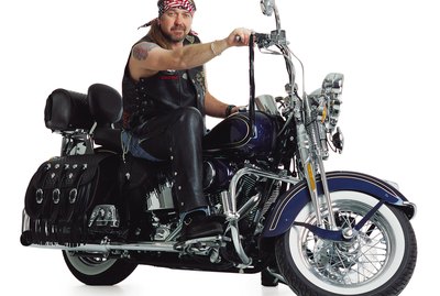 middle aged adult caucasian male sits on motorcycle smiles slightly at the camera