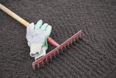 Garden rake and gloves on leveled soil