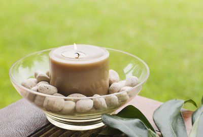 Bowl with candle and pebbles on table outdoors