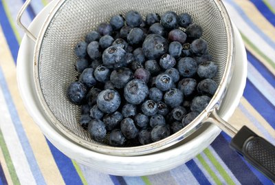 Freshly washed blueberries in vintage mesh strainer.