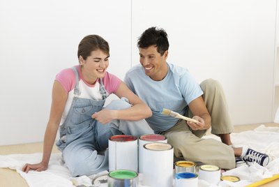 Couple sitting by paint pots in home