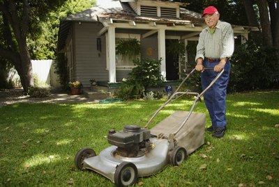 Portrait of elderly man mowing lawn