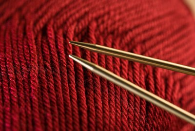 Knitting needles by red yarn