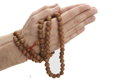 Man holding Buddhist prayer beads, close-up of hands
