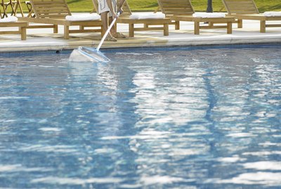 Man cleaning hotel outdoor pool with net