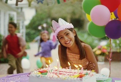 Girl (9-11) at birthday party, leaning over birthday cake, portrait