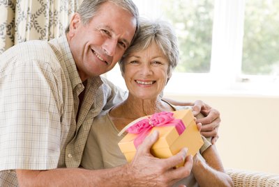 Husband giving wife gift in living room smiling
