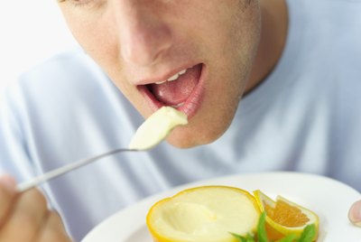Close-up of a young man eating orange sorbet with a spoon