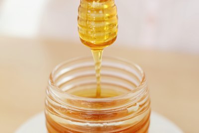 close-up of a honey dipper over a jar of honey