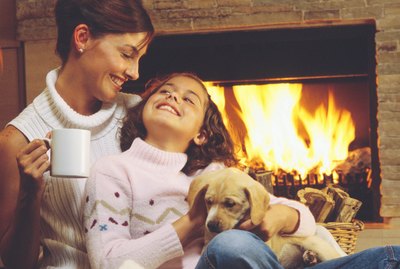 Mother and daughter with puppy by fireplace