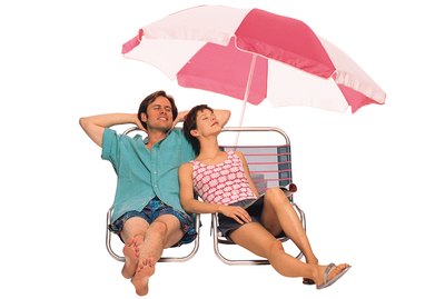 Couple reclining on lounge chairs under beach umbrella