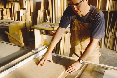 a carpenter cuts a board with a saw