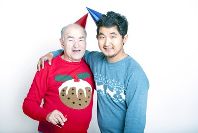 Portrait of a Senior adult man and a young man wearing Christmas jumpers and party hats