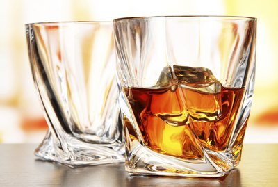 Glasses of whiskey, on bright background