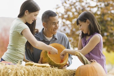 Girls and father carving pumpkins