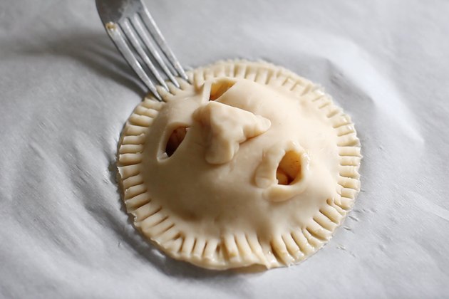Crimping edges of shrunken head pie with fork