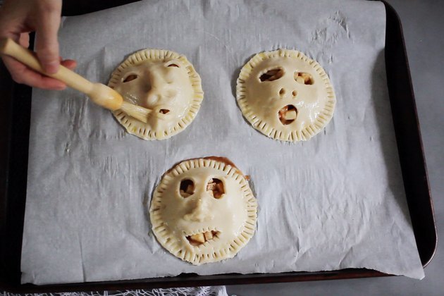 Brushing shrunken head pies with egg wash