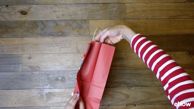 Attaching paper sweater to gift bag.