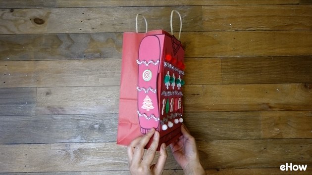 Attaching paper sweater to gift bag.