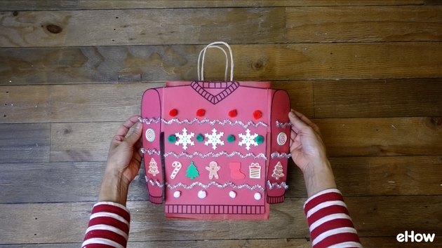 Attaching paper sweater to gift bag.
