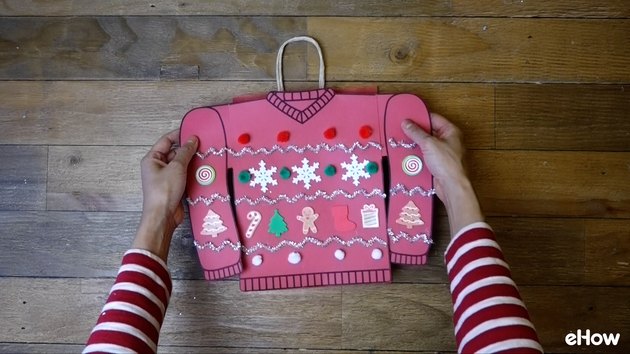 Attaching paper sweater to gift bag.