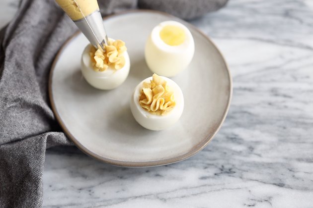 Piping egg yolk mixture into egg whites