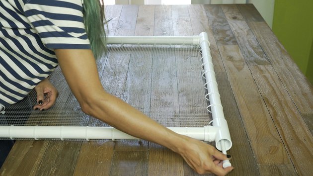 Inserting shower curtain tension rod into PVC frame for DIY PVC Pipe Pet Gate