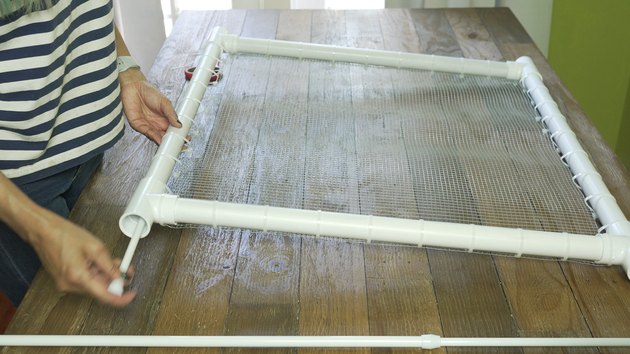 Inserting shower curtain tension rod into PVC frame for DIY PVC Pipe Pet Gate