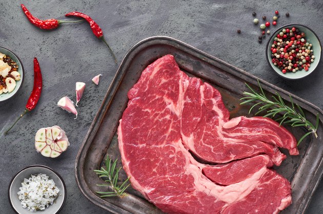 Raw steak. Meat with spices and herbs. Top view on black slate stone