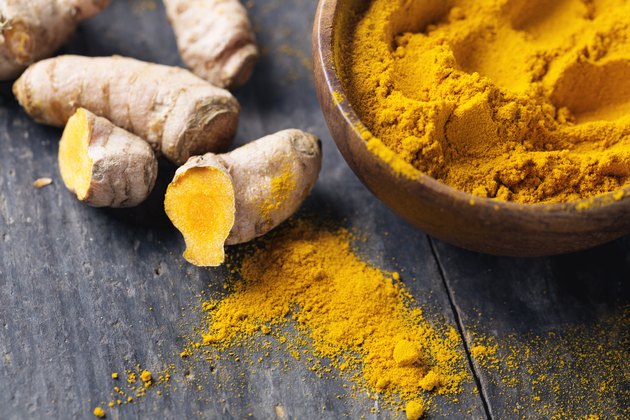 Spice: turmeric roots and powder on wood